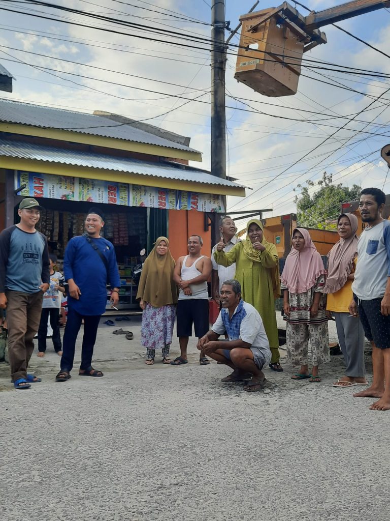 Foto Ketua RT 10 Adong Sinaga bersama warga saat pemasangan lampu jalan di Jalan Sisingamaraja.