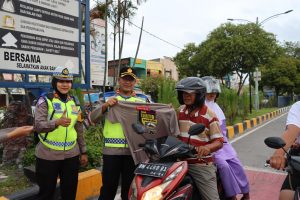 Foto Kapolres Dumai AKBP Nurhadi Ismanto, S.H., S.I.K didampingi Kasat Lantas Polres Dumai AKP Akira Ceria, S.I.K., M.M membagikan helm dan kaos kepada pengendara sepeda motor.