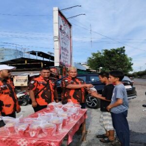 Foto : Ketua PAC Pemuda Pancasila Kecamatan Dumai Kota Asnur Mori (kanan) didampingi Sekretaris Ryan Pratama (tengah) memberikan takjil kepada salah satu warga.