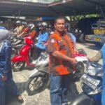 Foto : Ketua PAC Pemuda Pancasila Dumai Kota Asnur Memori memasang bendera merah putih di sepeda motor.