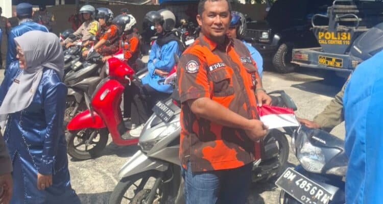 Foto : Ketua PAC Pemuda Pancasila Dumai Kota Asnur Memori memasang bendera merah putih di sepeda motor.