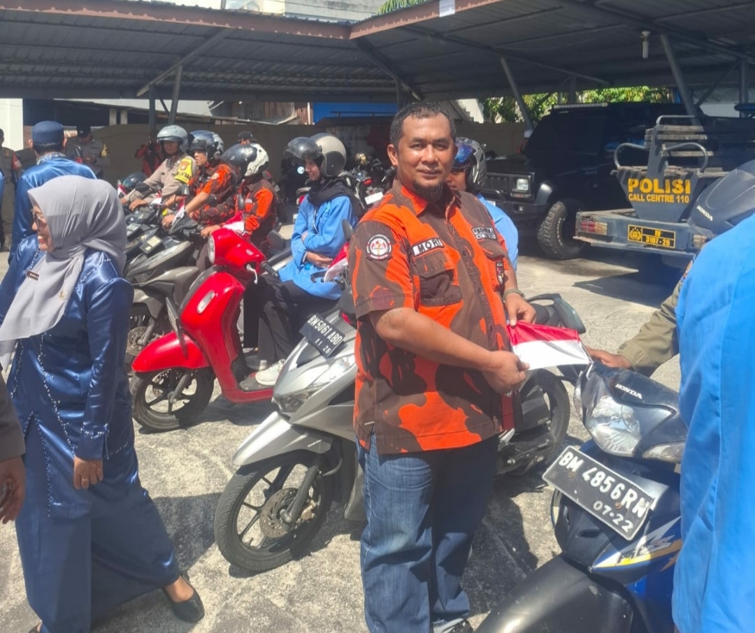 Foto : Ketua PAC Pemuda Pancasila Dumai Kota Asnur Memori memasang bendera merah putih di sepeda motor.